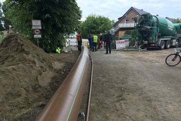 Das Rohr gleitet über Rollen. Gleichzeitig wird ein Leerrohr für Glasfaser mit eingezogen (rechts neben dem großen Rohr).