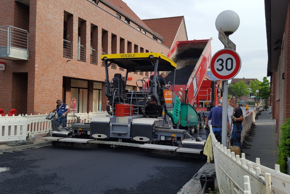 Der Asphaltfertiger schiebt sich langsam über die Straße und verteilt dabei gleichmäßig den Asphalt der Deckschicht. (Bild: Gemeinde Senden)